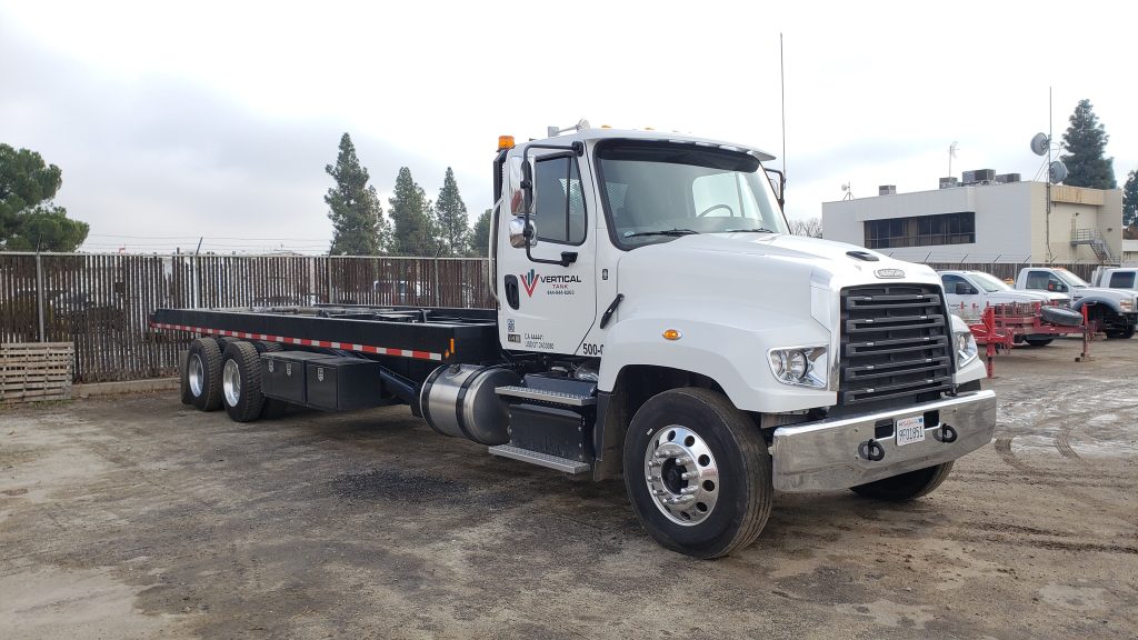 Tank delivery semi-truck arriving at a construction site with vertical tanks for setup